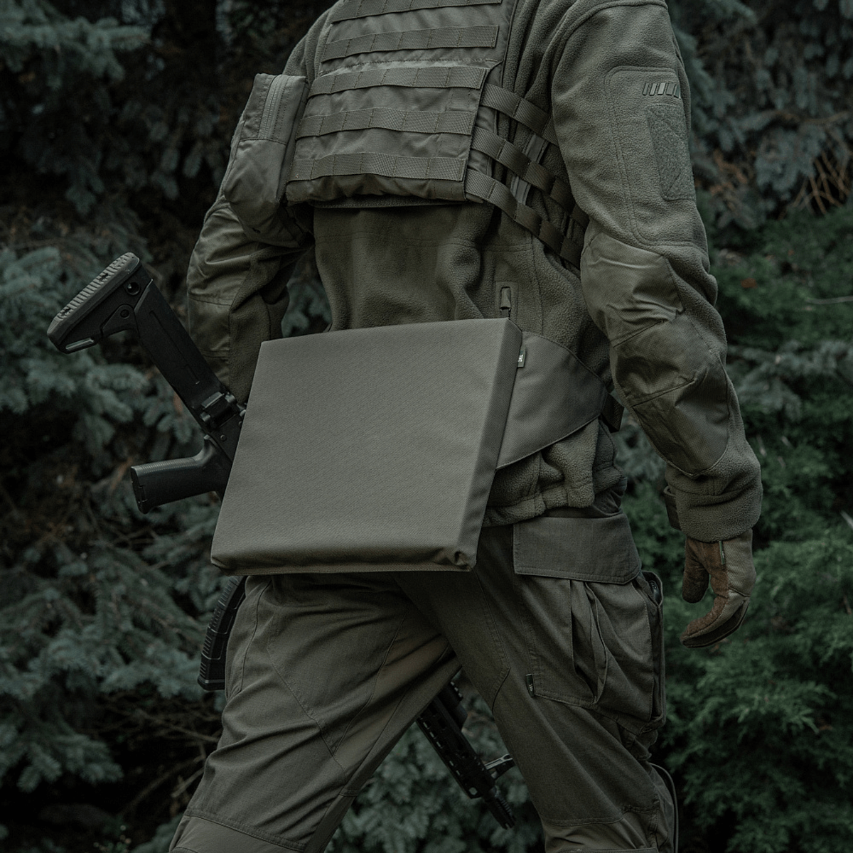 M-Tac Siddeunderlag med bælte til udendørs brug, båret af person i camouflagetøj i skovmiljø