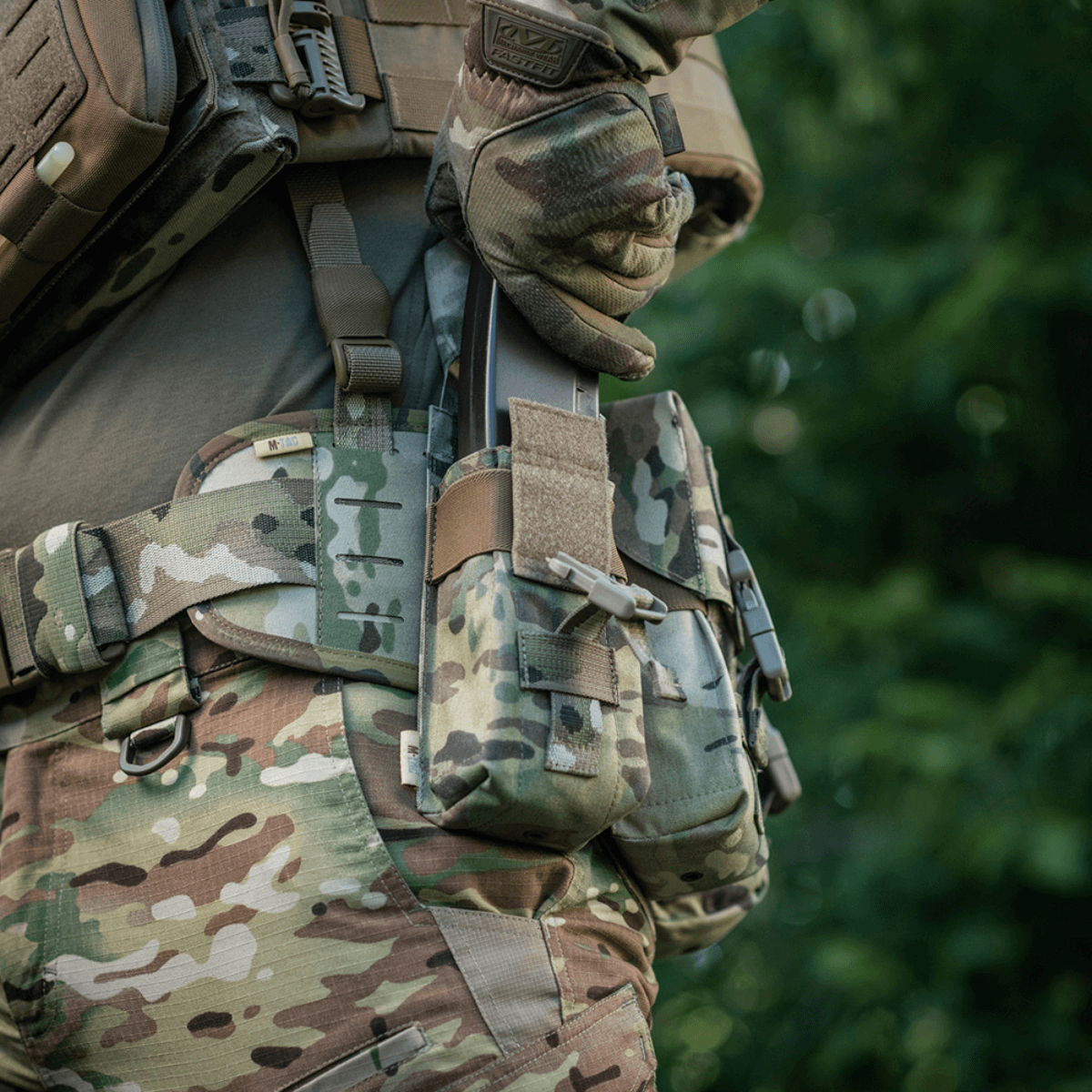 Person med M-Tac Dobbelt Magasin Taske med Fastex Lukning i camouflage for militær og outdoor brug.