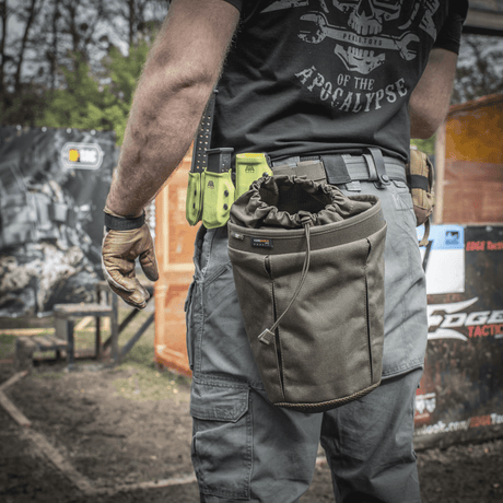 En person bærer en M-Tac Mag Drop Pouch Elite monteret på udstyr med MOLLE-fastgørelser for hurtig adgang til magasiner.