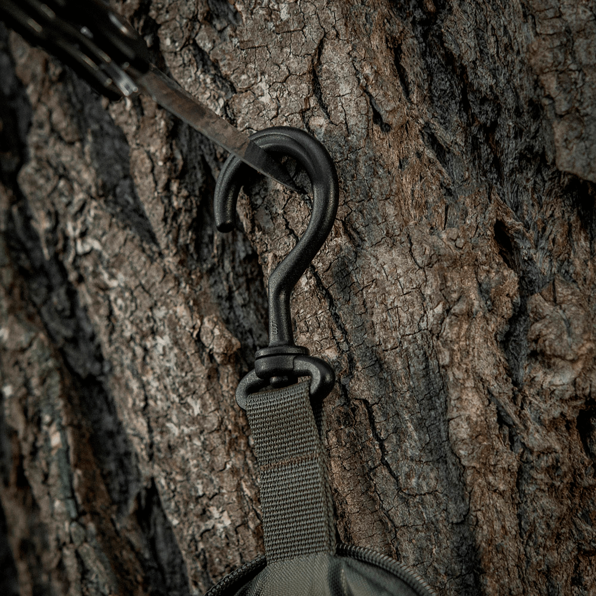 Robust krog på M-Tac Toilettaske Elite Gen.II hængende på træ, designet til nem rejseorganisering af hygiejneartikler.