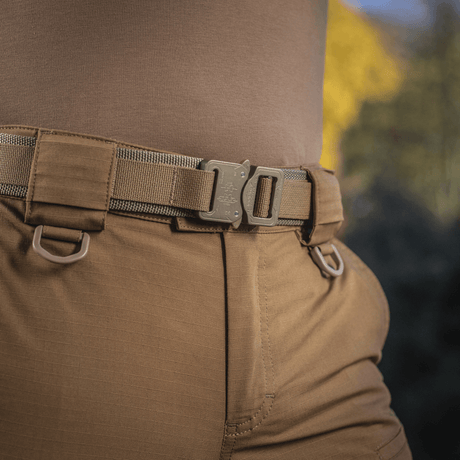 En person iført M-Tac Cobra Buckle Taktisk Bælte Laser Cut med AustriAlpin COBRA lås i udendørs miljø.