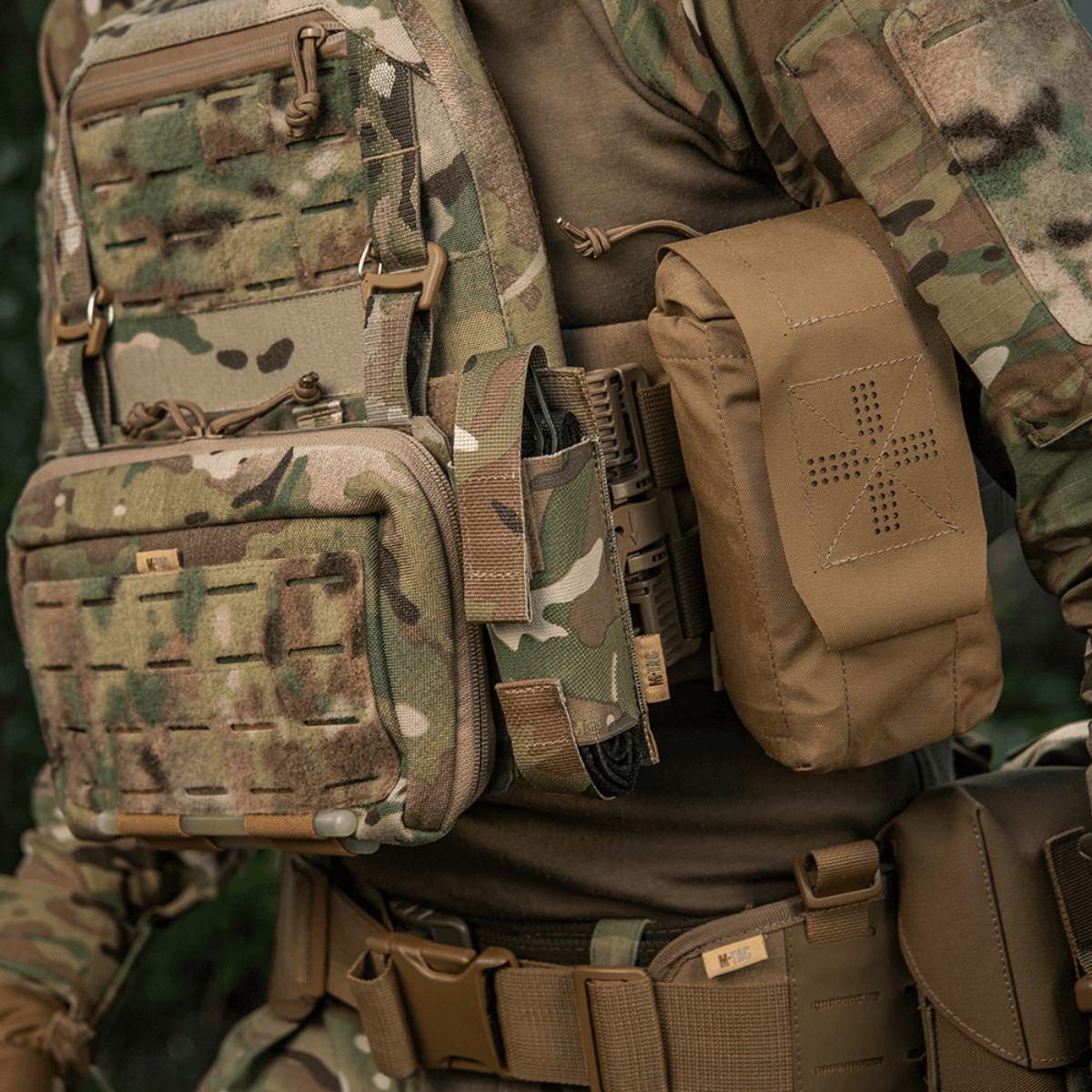 M-Tac Tourniquet Pouch Elastisk VELCRO Gen.II monteret på taktisk vest i skovkamouflage, lavet af robust Cordura 500D, hurtig adgang.