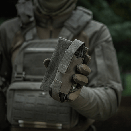 M-Tac Tourniquet Pouch Elastisk VELCRO Gen.II holdes af en taktisk udstyret person for hurtig adgang til tourniquet