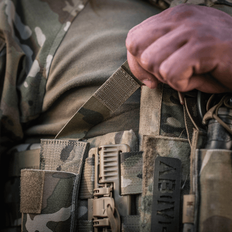 M-Tac Tourniquet Pouch Elastisk med MOLLE Gen.II i brug, set tæt på på camouflageudstyr. Ideel til hurtig adgang til tourniquet.
