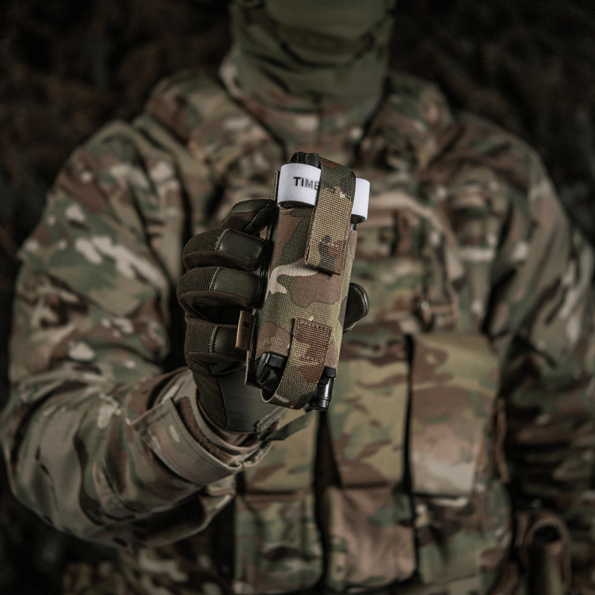 Soldat i camouflageuniform holder M-Tac Elastisk Tourniquet Pouch Molle Gen.III op foran, klar til hurtig adgang.