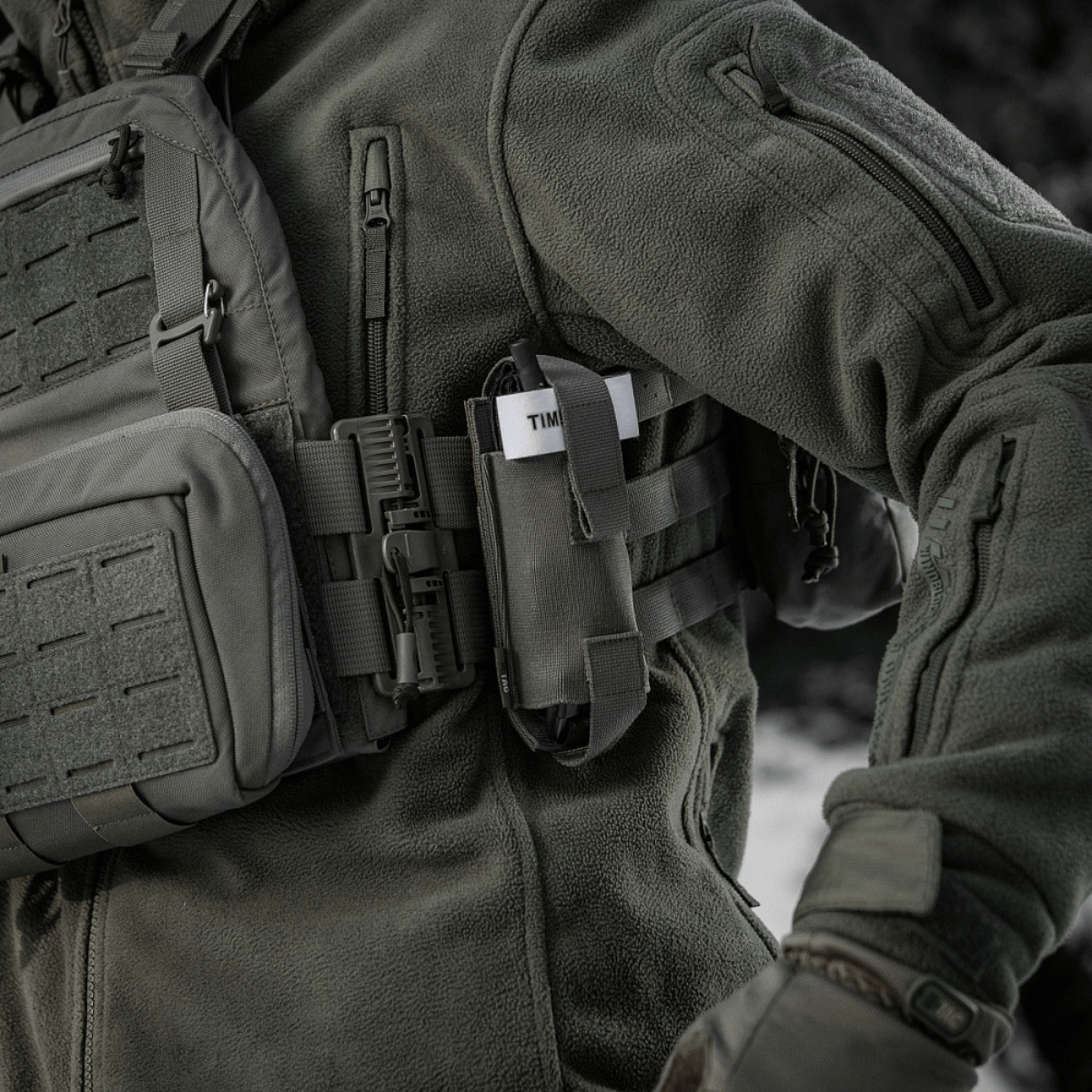 M-Tac Elastisk Tourniquet Pouch Molle Gen.III fastgjort til taktisk jakke på person i felten.