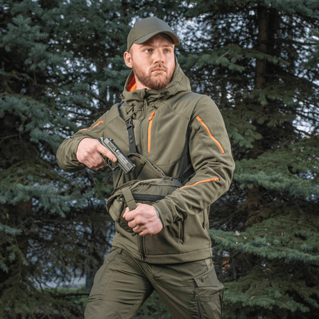 Mand bærer M-Tac Sphaera Hex Hardsling Taske Gen.II Elite i skov, klar til hurtig handling med skjult bæresystem.