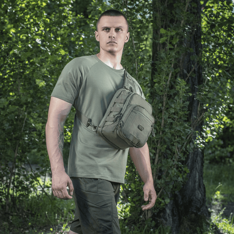 Mand bærer M‑Tac Cross Bag Elite Hex i skovmiljø, ideel til daglig brug og taktisk udstyr.