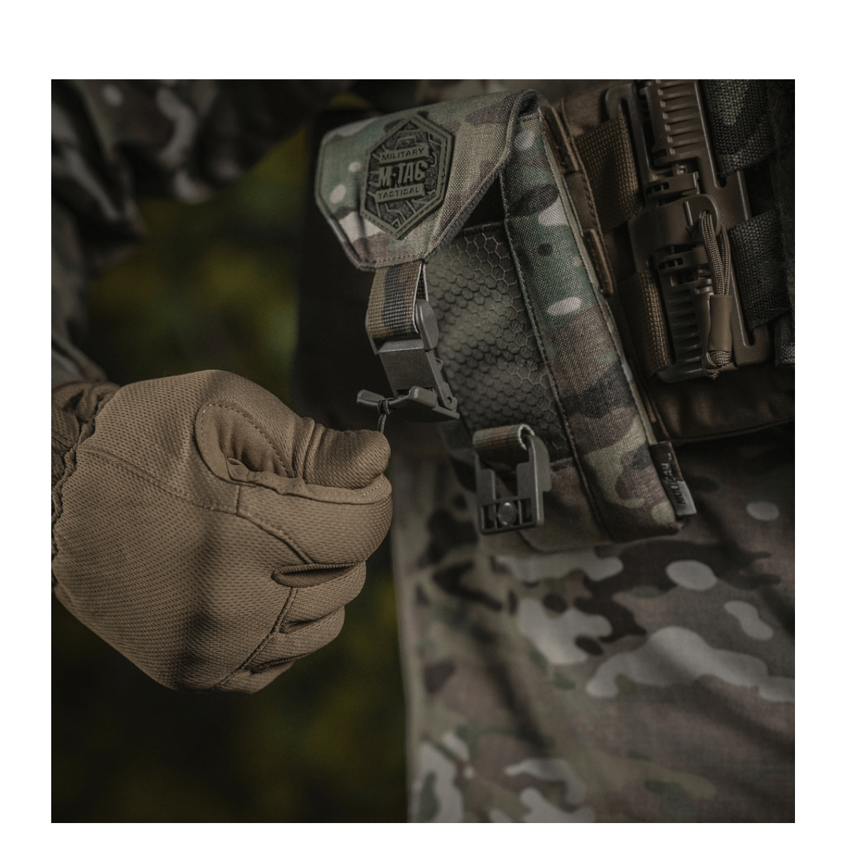 Mand i camouflage-tøj demonstrerer M-Tac Smartphone Lomme Elite Large Hex med magnetisk spænde til ekstra sikkerhed.