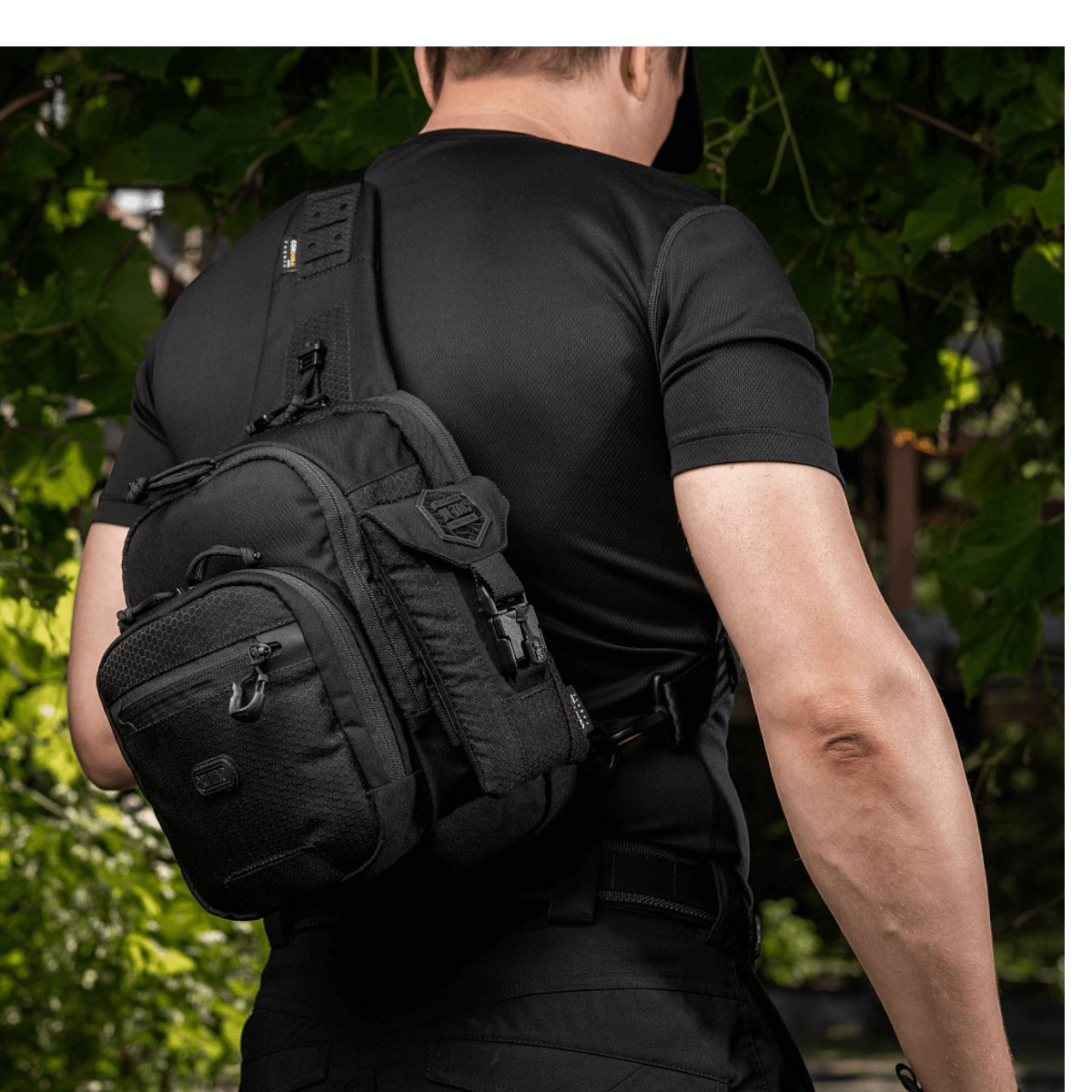 M-Tac Smartphone Lomme Elite Large Hex sort taske bæres af en person i udendørs miljø, lavet af slidstærkt Cordura materiale.