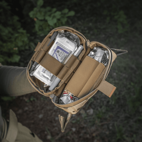 M‑Tac Horizontal Medical Pouch Elite i brug, åben taske viser indhold af feltkit til førstehjælp i Cordura 500D med YKK AquaGuard lynlås.