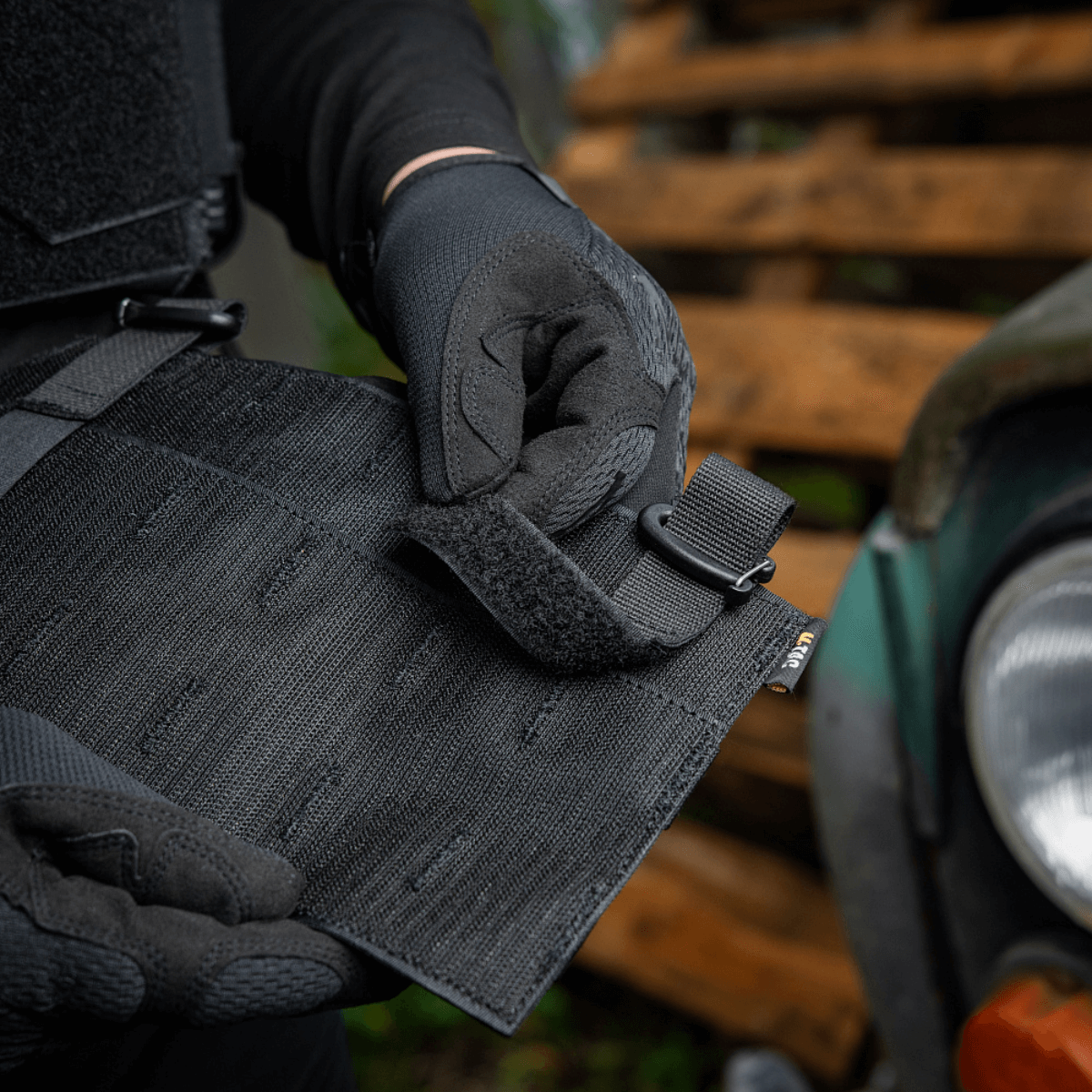 En person justerer M‑Tac Front Panel til Cuirass QRS med Woojin kroge og Velcro, lavet af Cordura 500D, til militært brug.