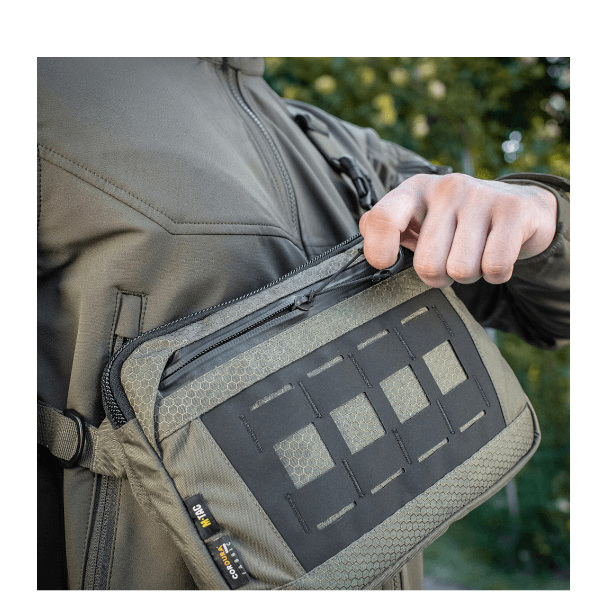 Mand åbner M-Tac Admin Taske Elite lavet af slidstærk Cordura, viser stilfuldt og funktionelt design med justerbar skulderrem.