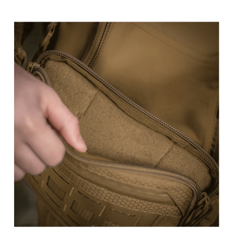 Person åbner lomme på M-Tac Admin Taske Elite lavet af slidstærkt Cordura materiale med YKK lynlåse.