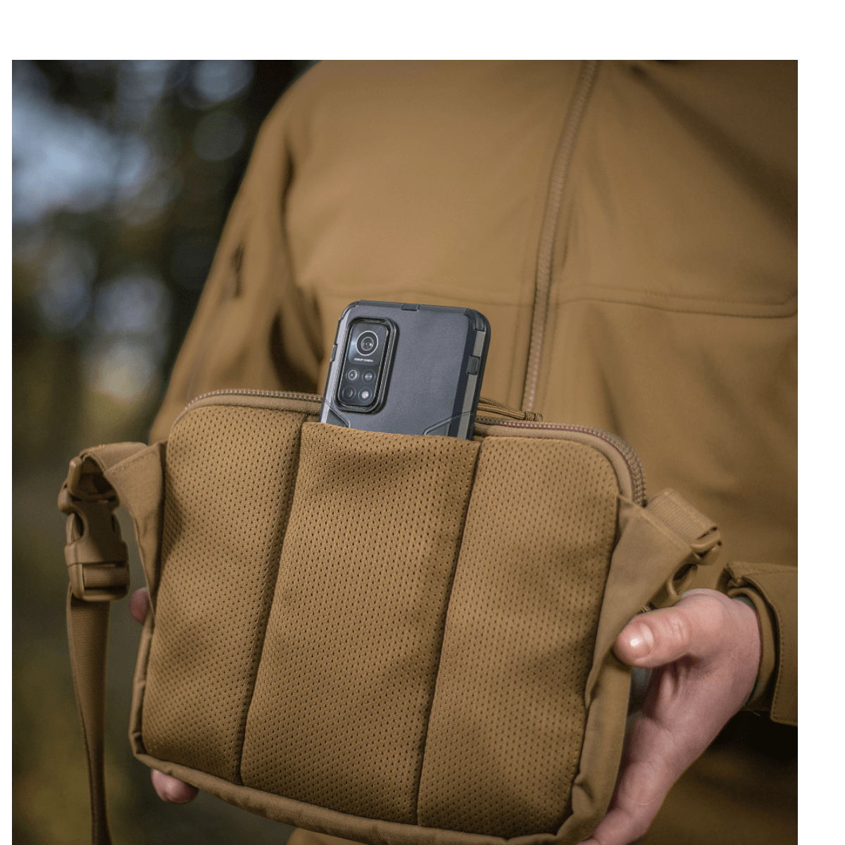 M-Tac Admin Taske Elite med mobiltelefon i lommen, stilfuldt design og holdbart materiale, perfekt til udendørsaktiviteter.