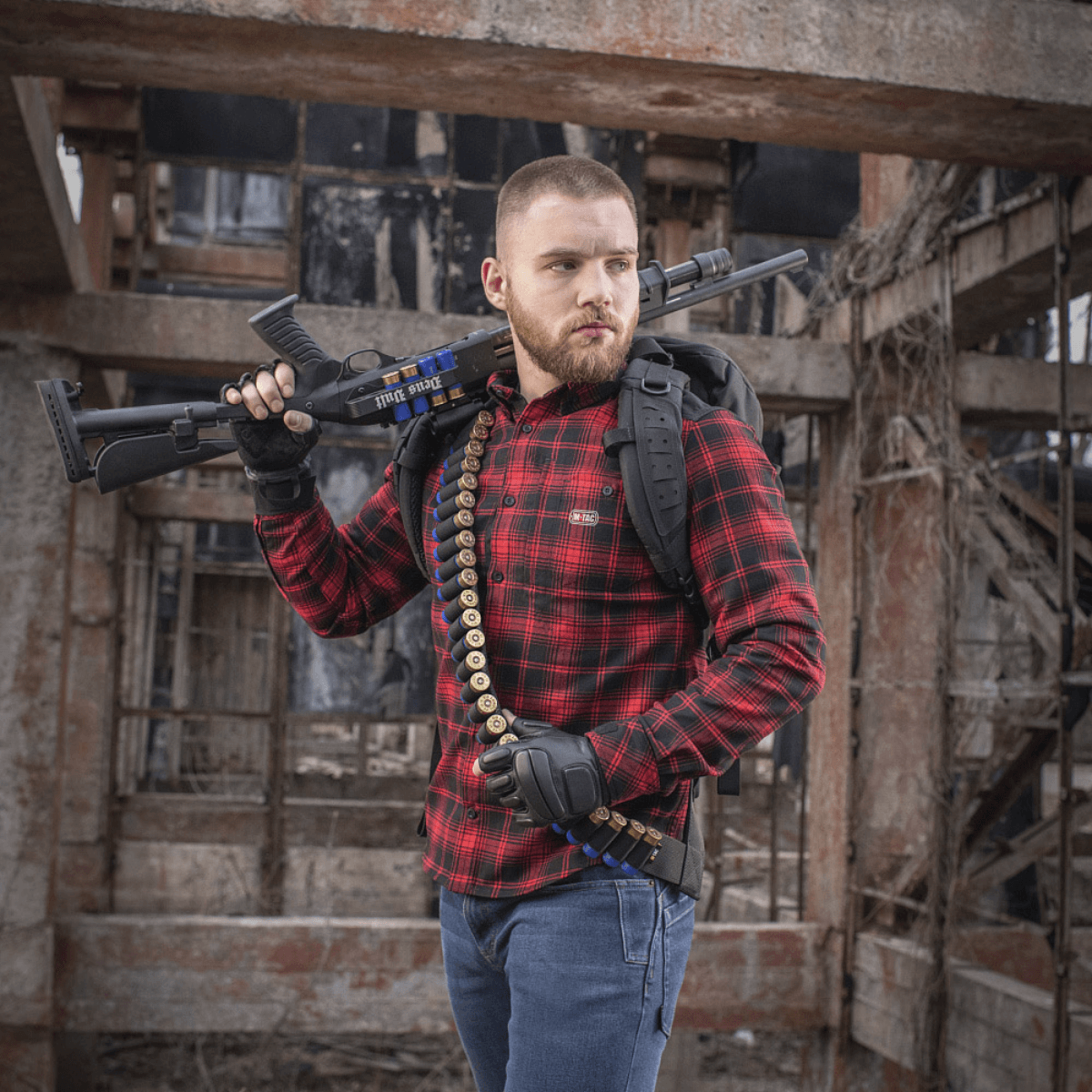 Mand bærer M-Tac Bandolier Elite og skydevåben i industrielt miljø, designet til hurtig adgang til ammunition.