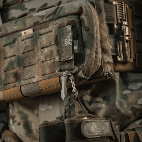 M-Tac Karabinhage Tilbehør fastgjort på taktisk rygsæk med MOLLE-system, nem åbning og justerbar Velcro-rem for sikker brug.