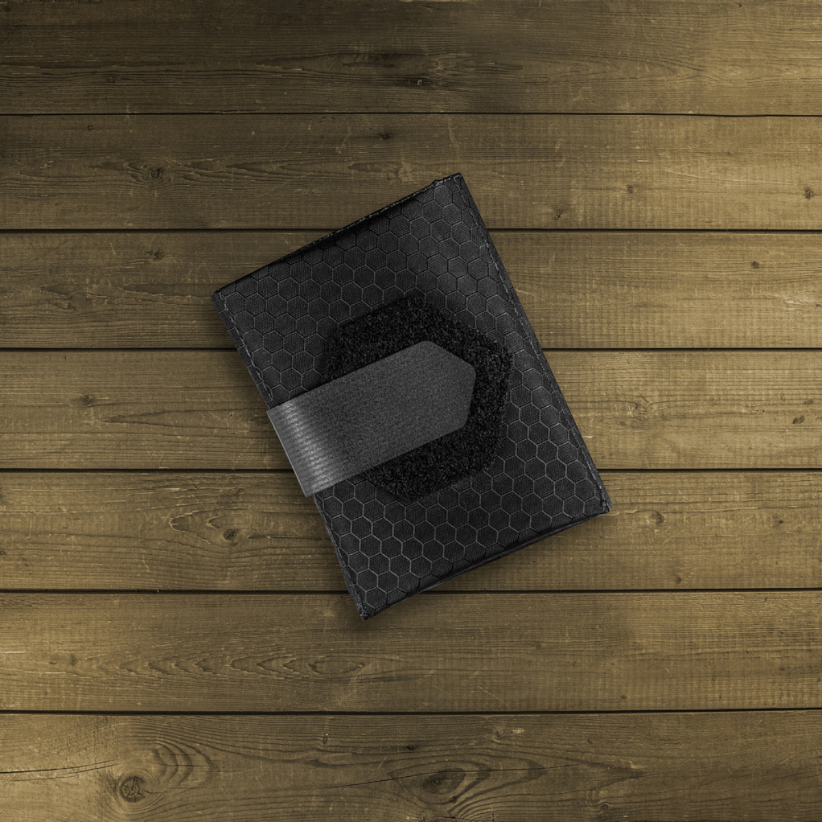 M-Tac City Med Pouch Hex, bærbart førstehjælpskit i slidstærkt Hex Polyester med Velcro-lukning, set på træbaggrund.