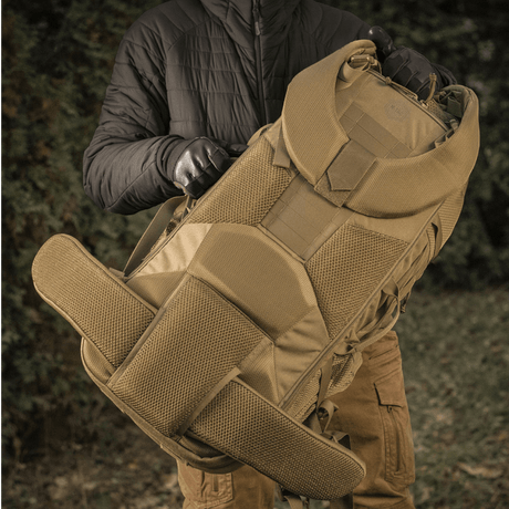 Person holder M-Tac Rygsæk Large Elite Hex Gen. IV lavet af robuste materialer, velegnet til bæring af våben i naturen.