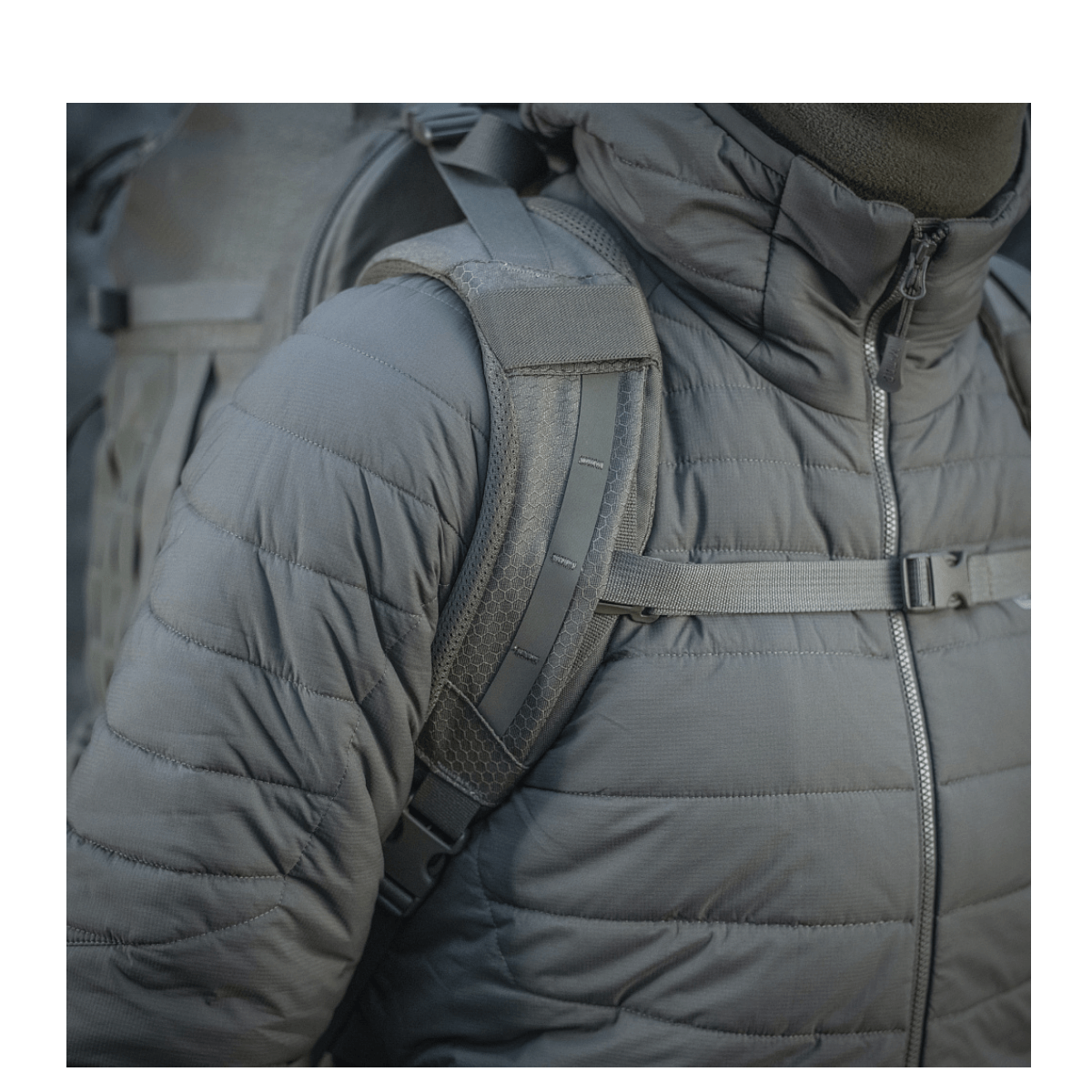 Person med M-Tac Rygsæk Large Elite Hex Gen. IV iført grå jakke, highlighting taskens ergonomiske remme og robust design.