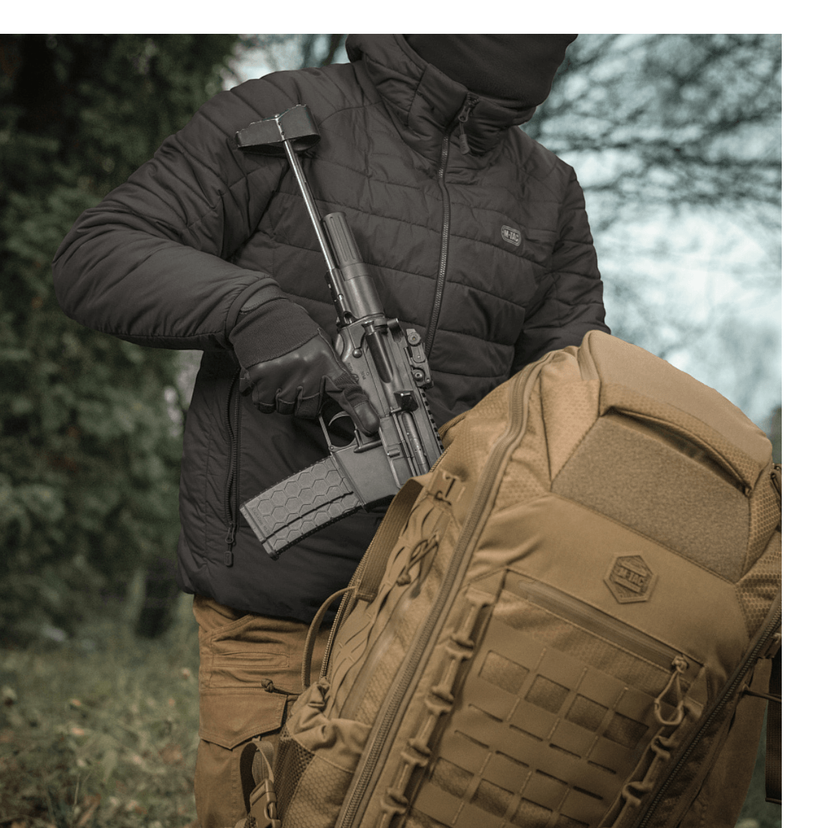 Person med M-Tac Rygsæk Large Elite Hex Gen. IV og adskilt våben i skov, viser taskens bæreevne og slidstærk kvalitet.