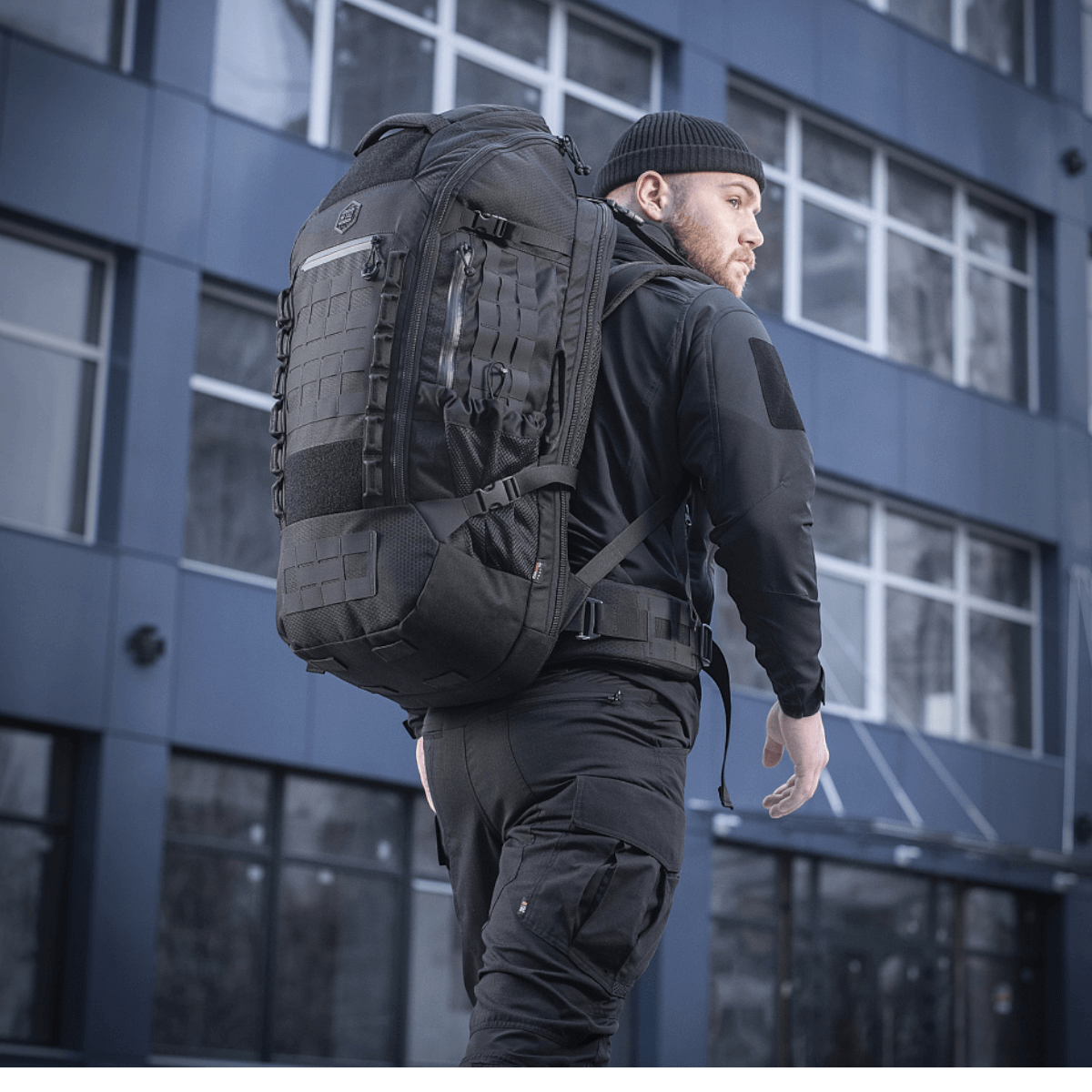 Mand bærer M-Tac Rygsæk Large Elite Hex Gen. IV i sort, ergonomisk designet til funktionalitet og holdbarhed, set i urbant miljø.