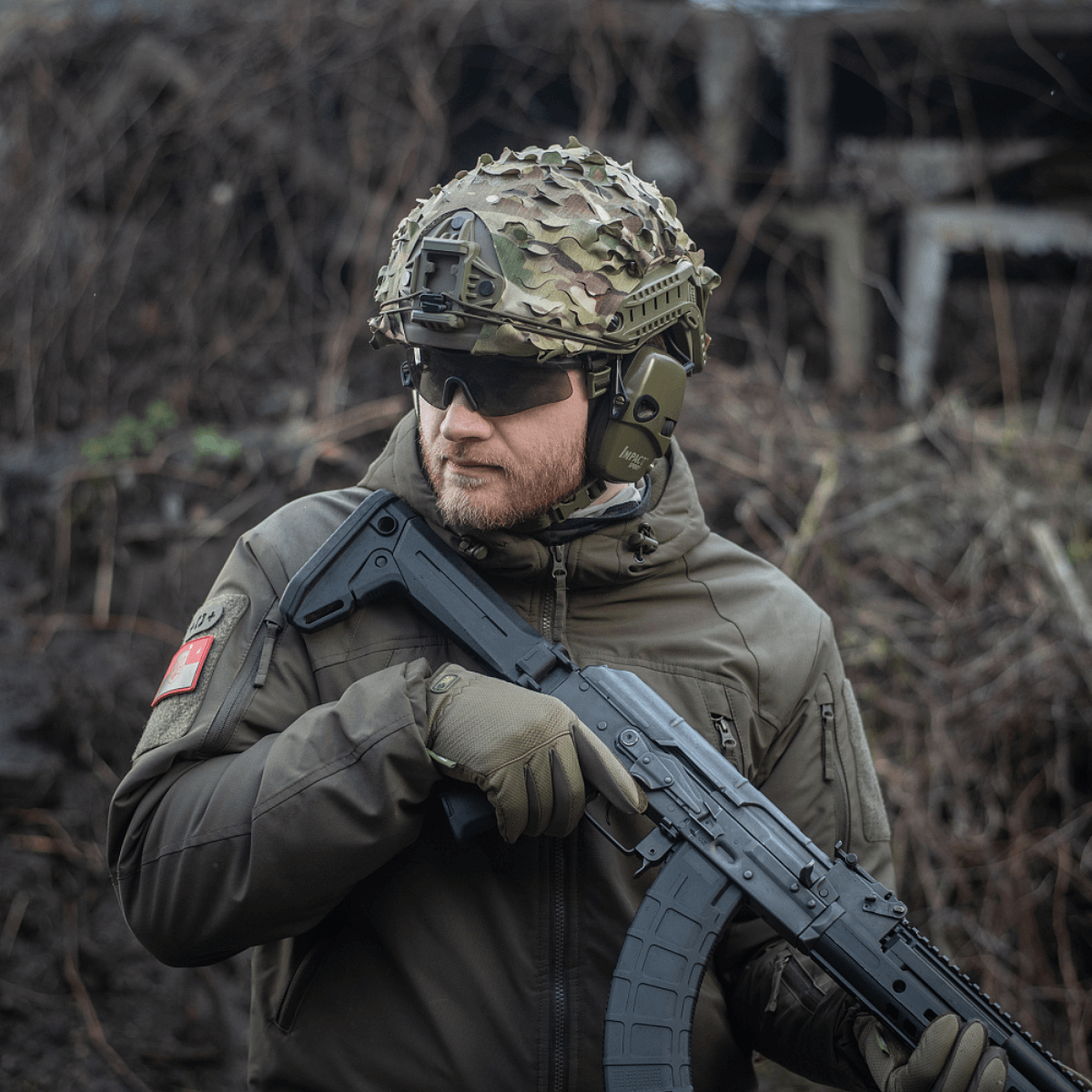 Soldat iført M‑Tac Vilha Hjelmdække FAST med MULTICAM mønster, tilpasset FAST-hjelm. Camoufleret på ujævnt terræn.