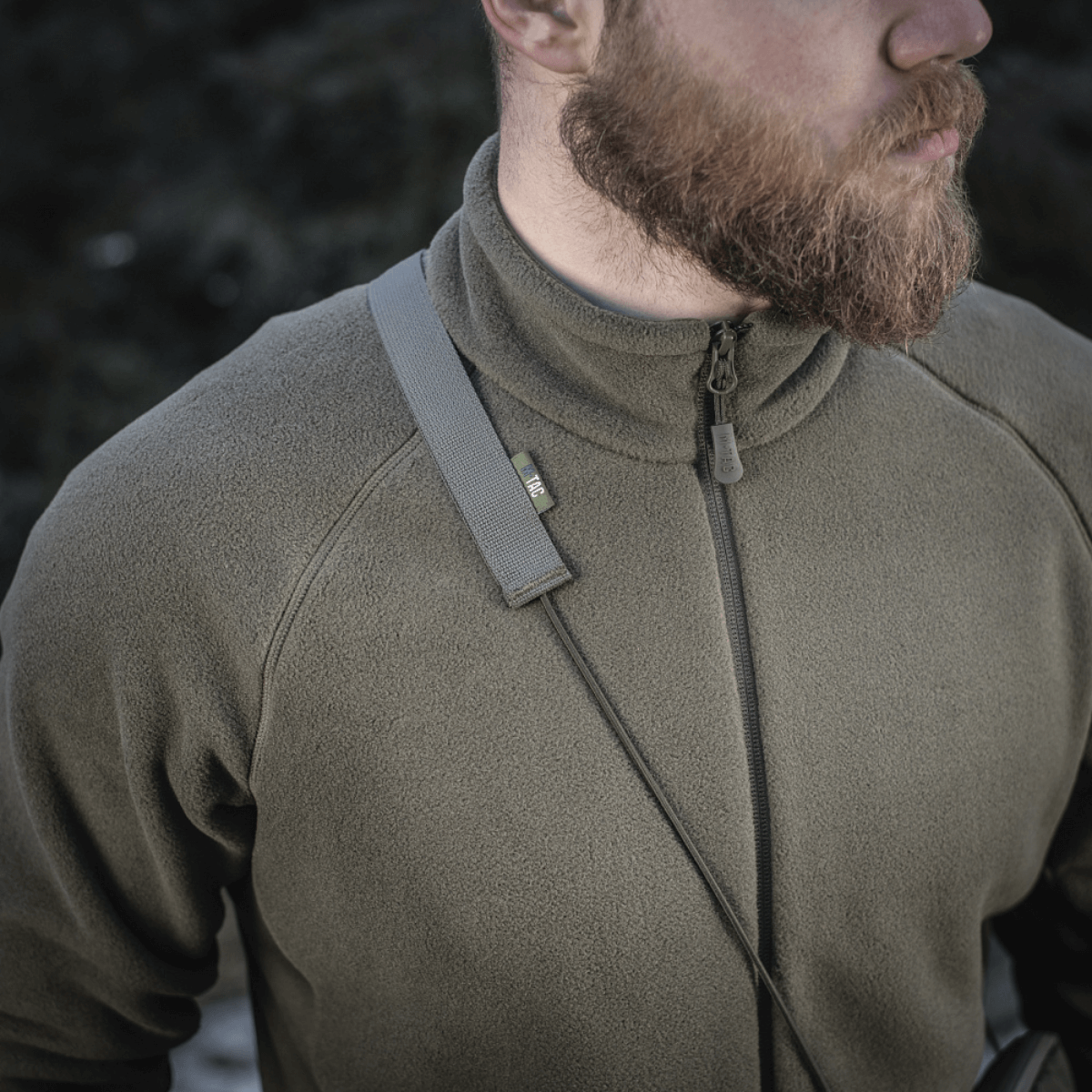 Mand bærer en grøn fleece med M‑Tac Pocket Bag Elite HEX remmen over skulderen, viser holdbarhed og stil.