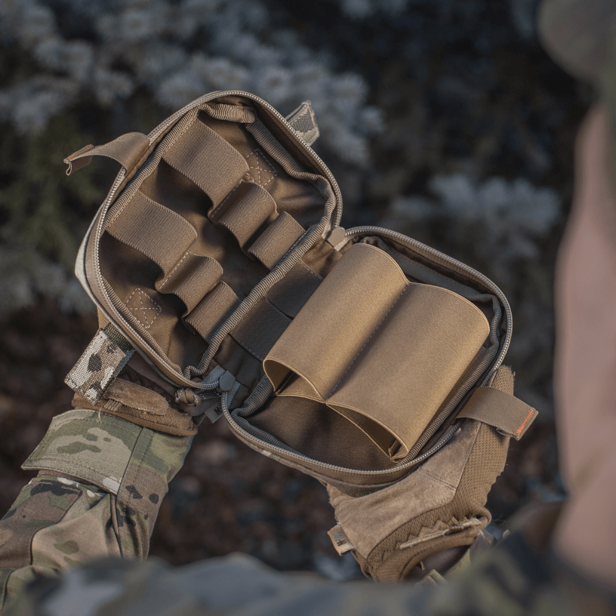 Åbnet M-Tac Horisontal Medic Lomme Large Elite i Cordura 500D, med indvendig organizer til førstehjælpssæt, holdt af soldat.