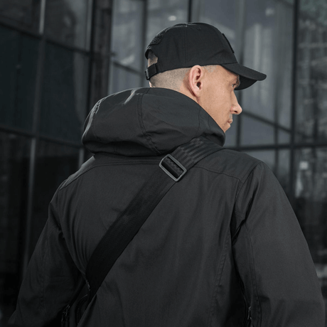Person i sort jakke bærer M-Tac Tablet Bag Laser Cut Hex med justerbar rem, ideel til EDC og hurtig adgang.