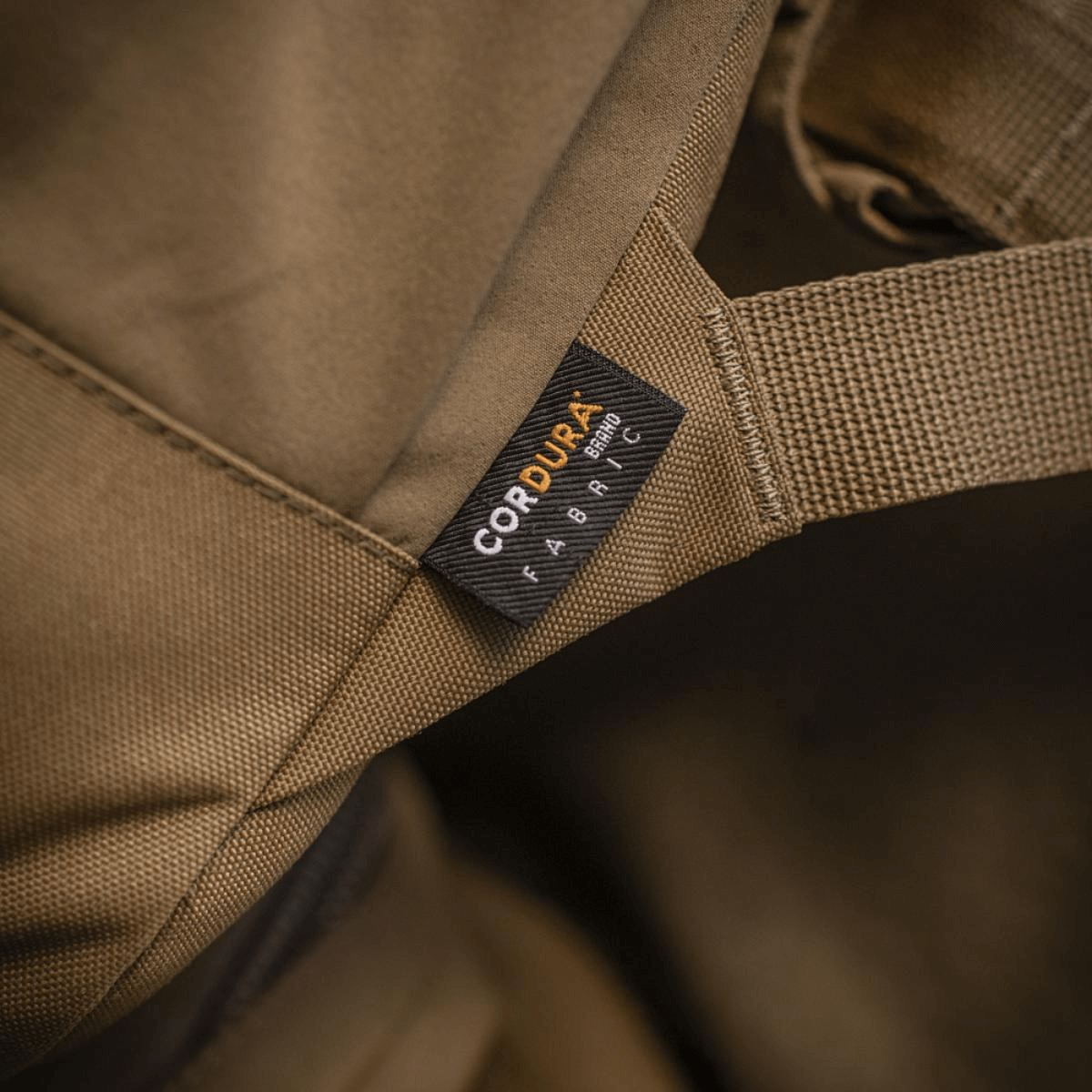 Nærbillede af brun Cordura-stofmærke på en robust taske eller rygsæk, der viser holdbarhed og kvalitet.