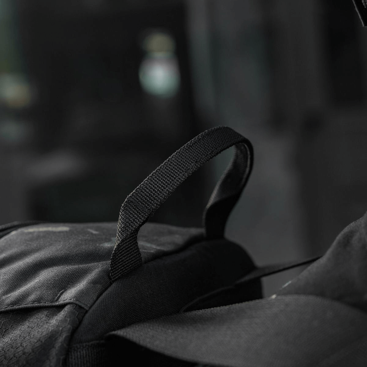 Sort rygsæk og strop i fokus med sløret baggrund