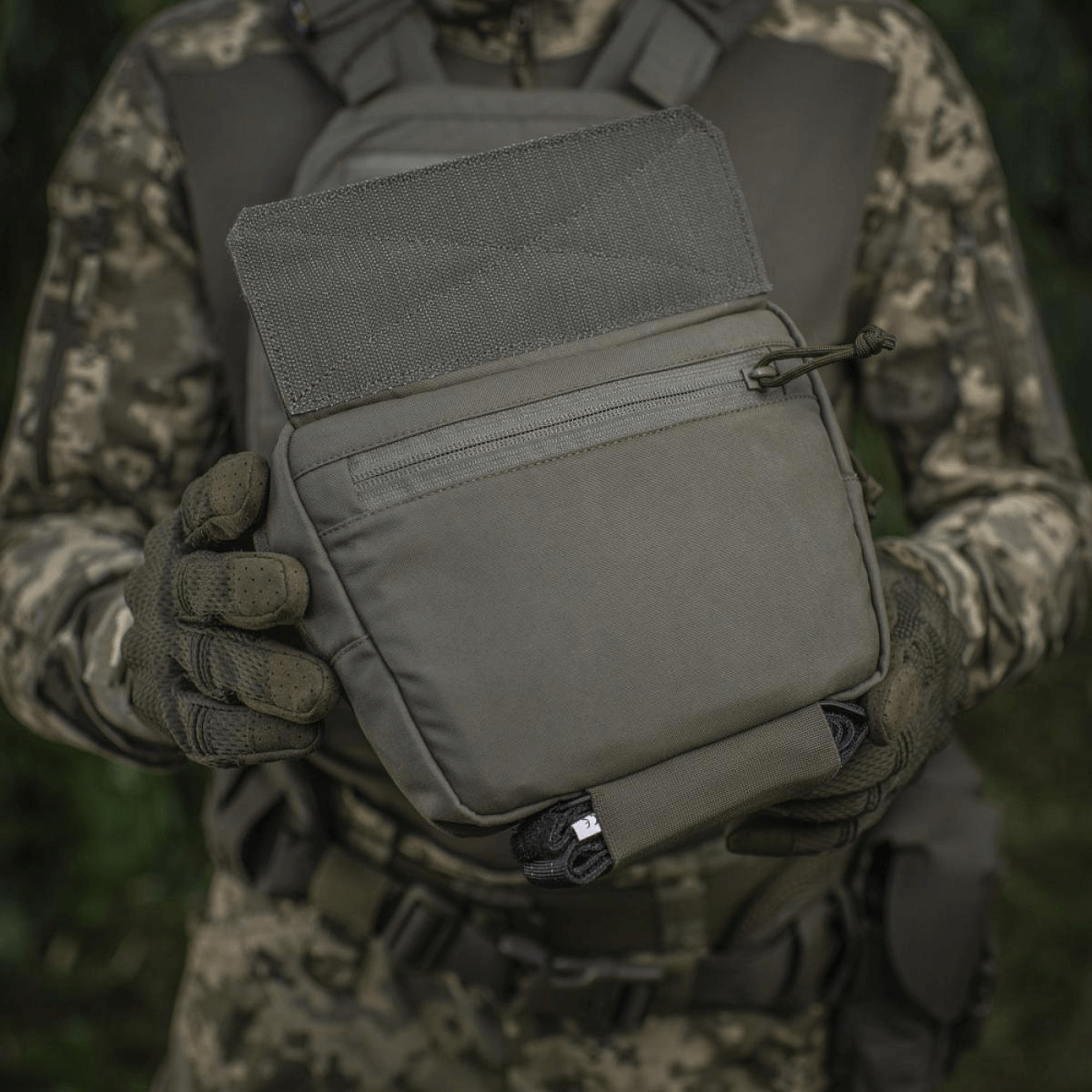 M-Tac Large Elite Gen.II Skuldertaske holdt af person i camouflage, fremstillet af slidstærkt Cordura 500D material med YKK lynlåse.