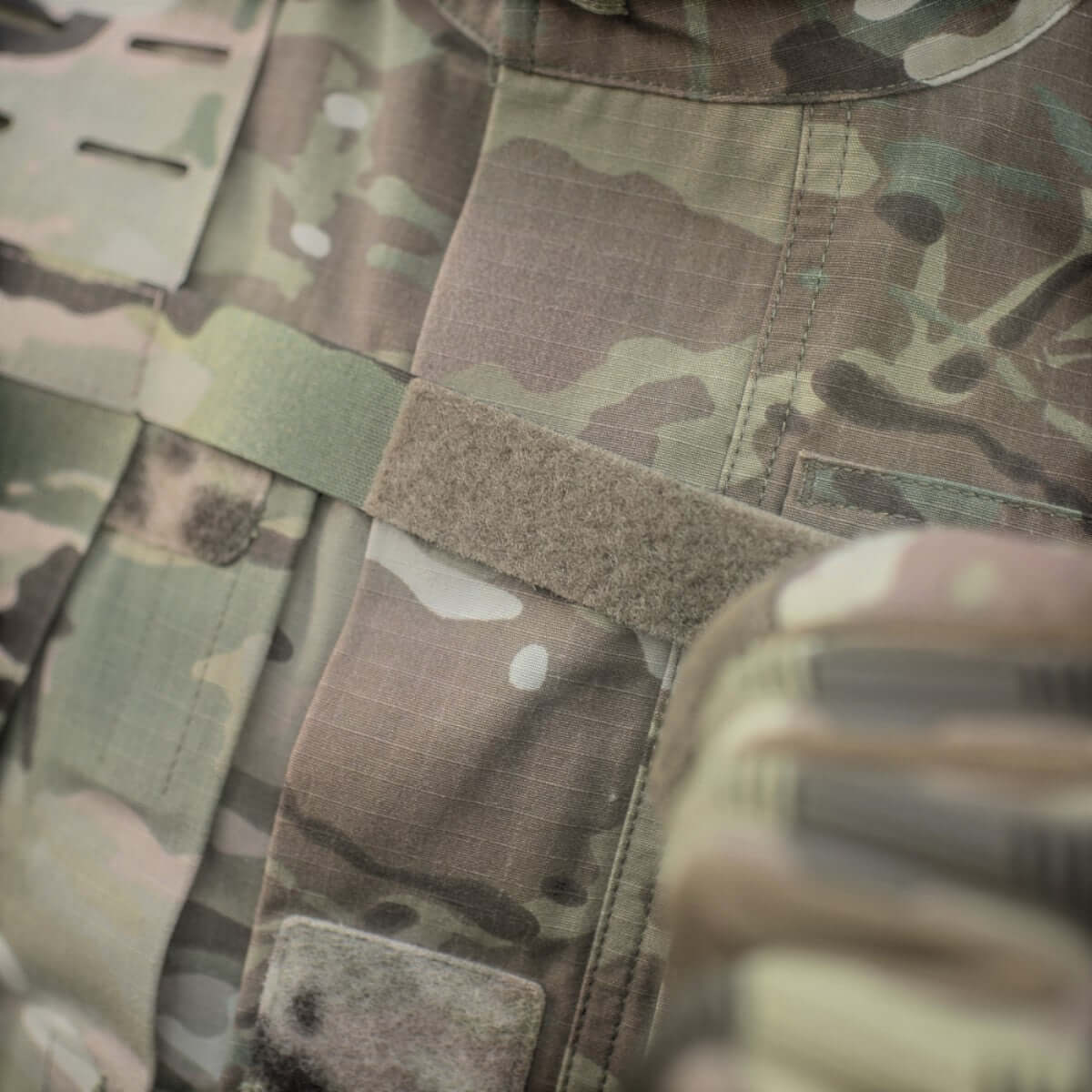 Nærbillede af taktisk vest med MOLLE-interface og camouflagedesign, der viser M-Tac Skulderstropper til taktisk bælte Laser Cut.