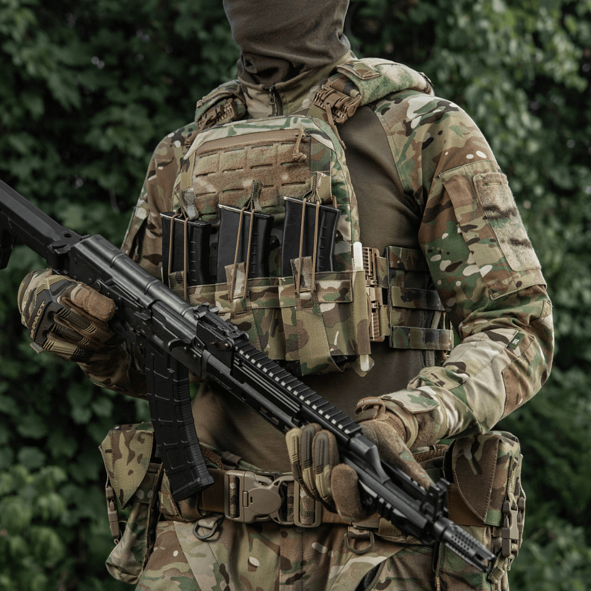 Soldat i fuldt udstyr med M-Tac Frontpanel til Cuirass QRS Pladebærer Tre Magasiner og riffel i skovområde