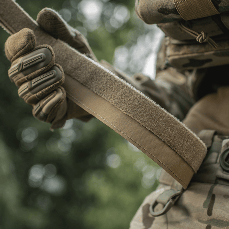 M‑Tac Internal Tiger Bælte holdes af taktisk klædt person, perfekt til militær og taktisk brug.