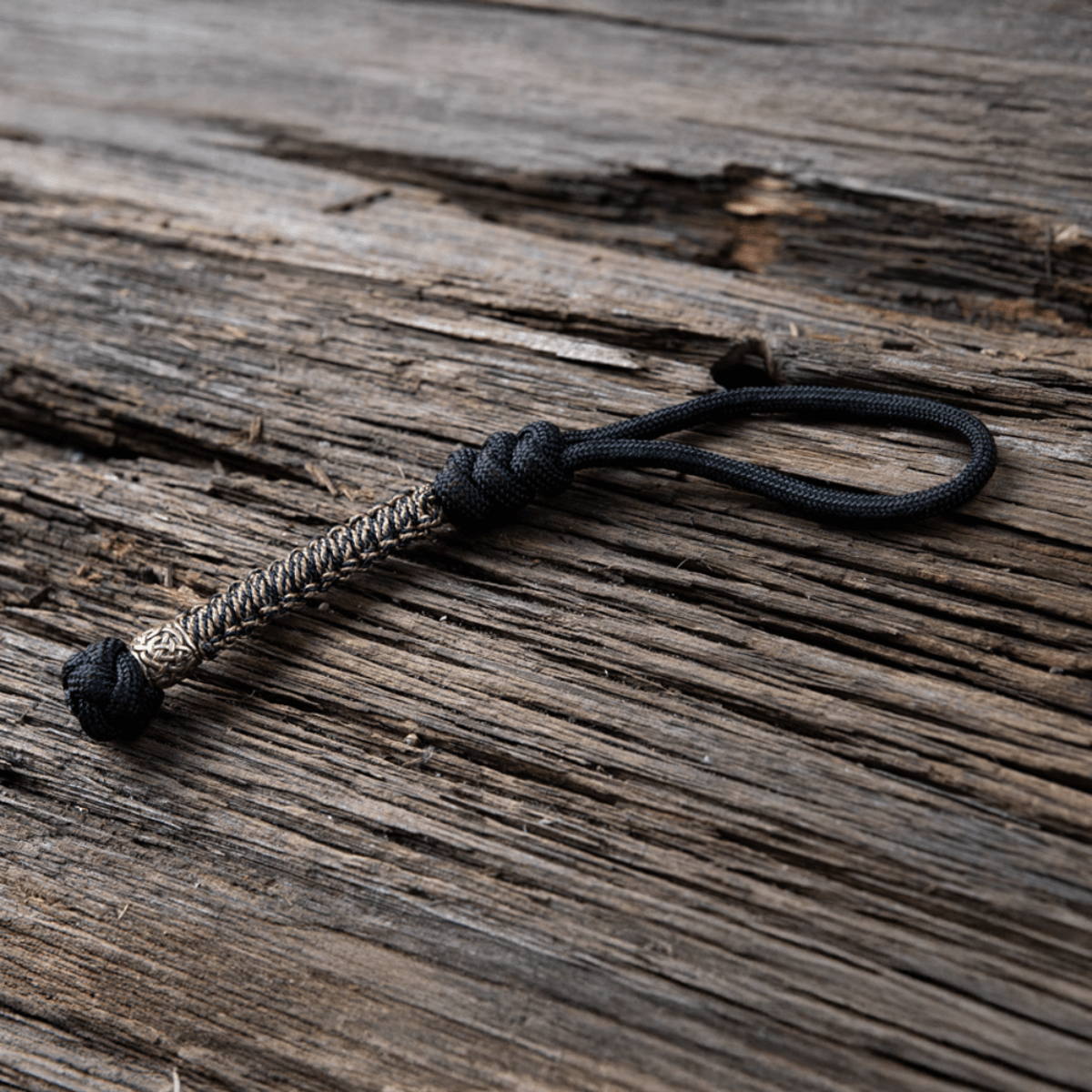 M-Tac Knife Lanyard Scandinavian i flettet paracord, et stilfuldt og praktisk tilbehør til lommeknive på træbaggrund.