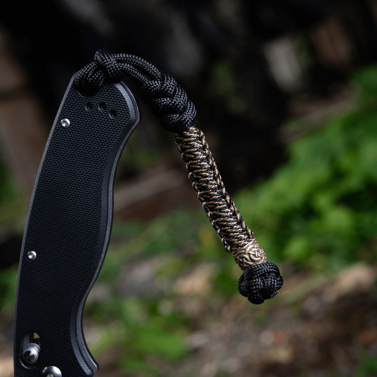 M-Tac Knife Lanyard Scandinavian med flettet paracordstil på lommeknivens skaft i naturlig skovbaggrund