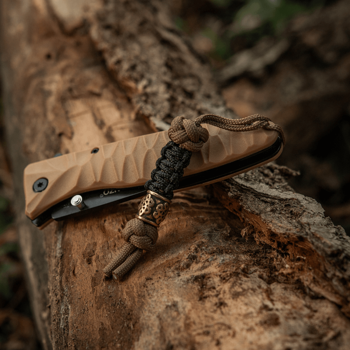 M-Tac Lanyard Scandinavian Small Chinese Knot on a brown pocket knife with decorative bead for outdoor use.