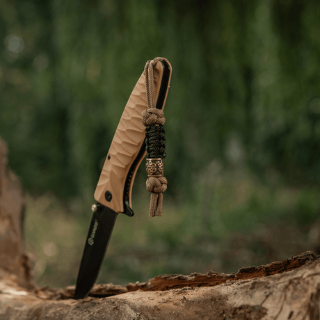 M-Tac Lanyard Scandinavian Small Chinese Knot på en kniv, lavet af snoet paracord og udsmykket med skandinaviske motiver i naturmiljø.