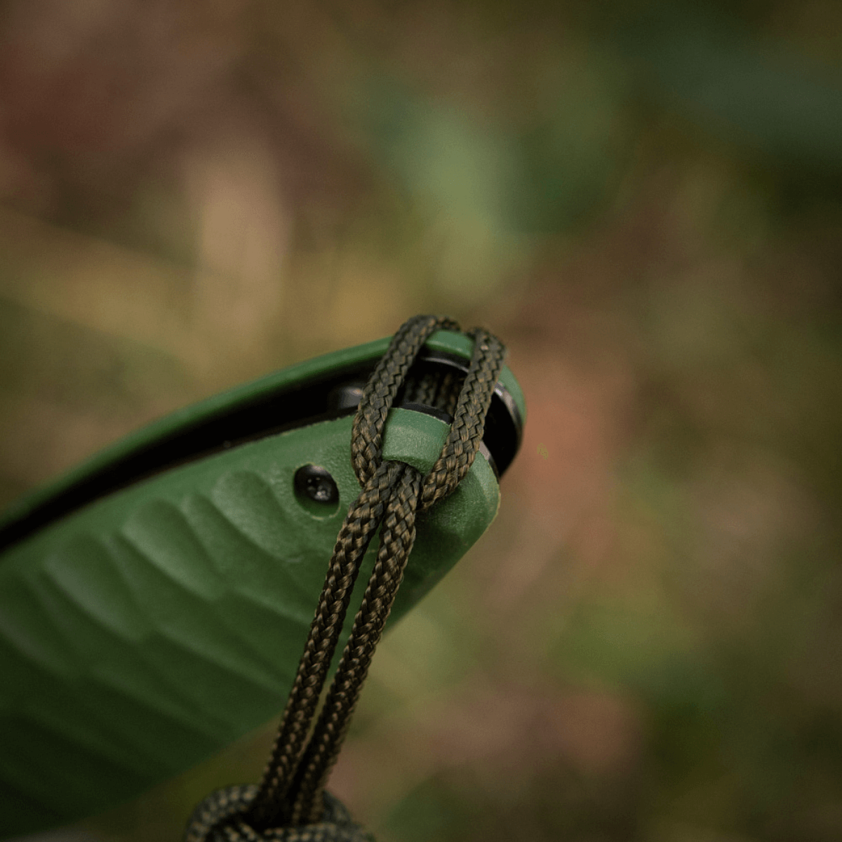 M-Tac Knife Lanyard Celtic på en grå kniv til udendørs brug, fremhæver et stilfuldt, flettet design lavet af holdbar paracord.