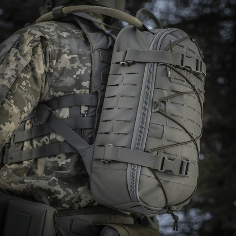 M-Tac Rygsæk Sturm Elite Gen.II bæres af en person i militært udstyr, grå farve, udstyret med MOLLE system og elastisk snøring.