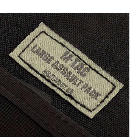 Etiketten på M-Tac Large Assault Pack Rygsæk i nærbillede, der viser produktets logo og navnetekst.