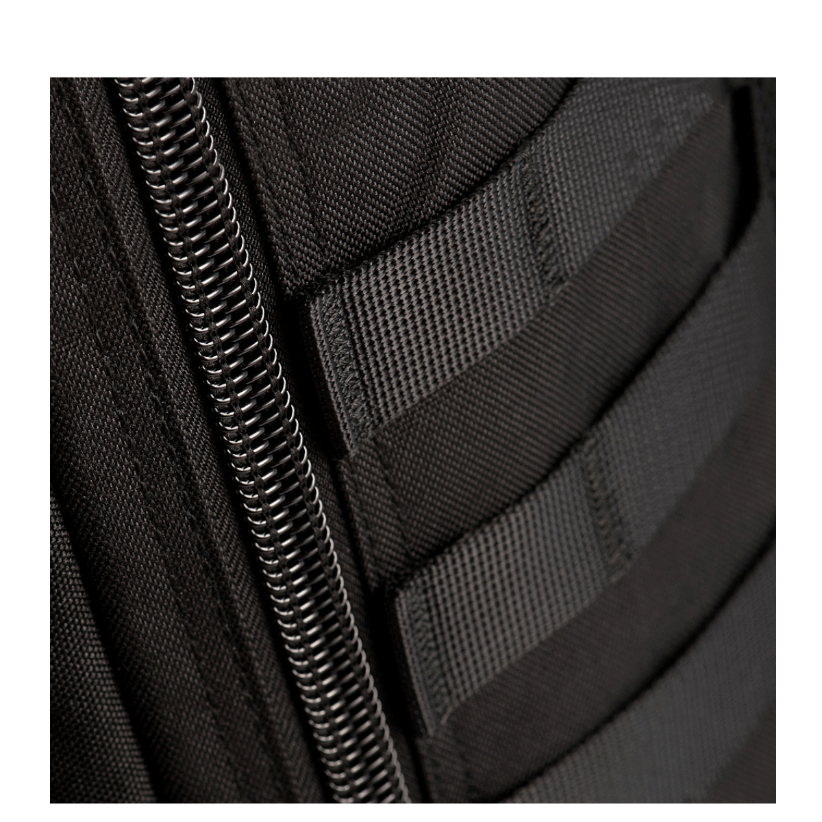 Nærbillede af lynlås og MOLLE system på M-Tac Large Assault Pack Rygsæk, sort farve og holdbare materialer.