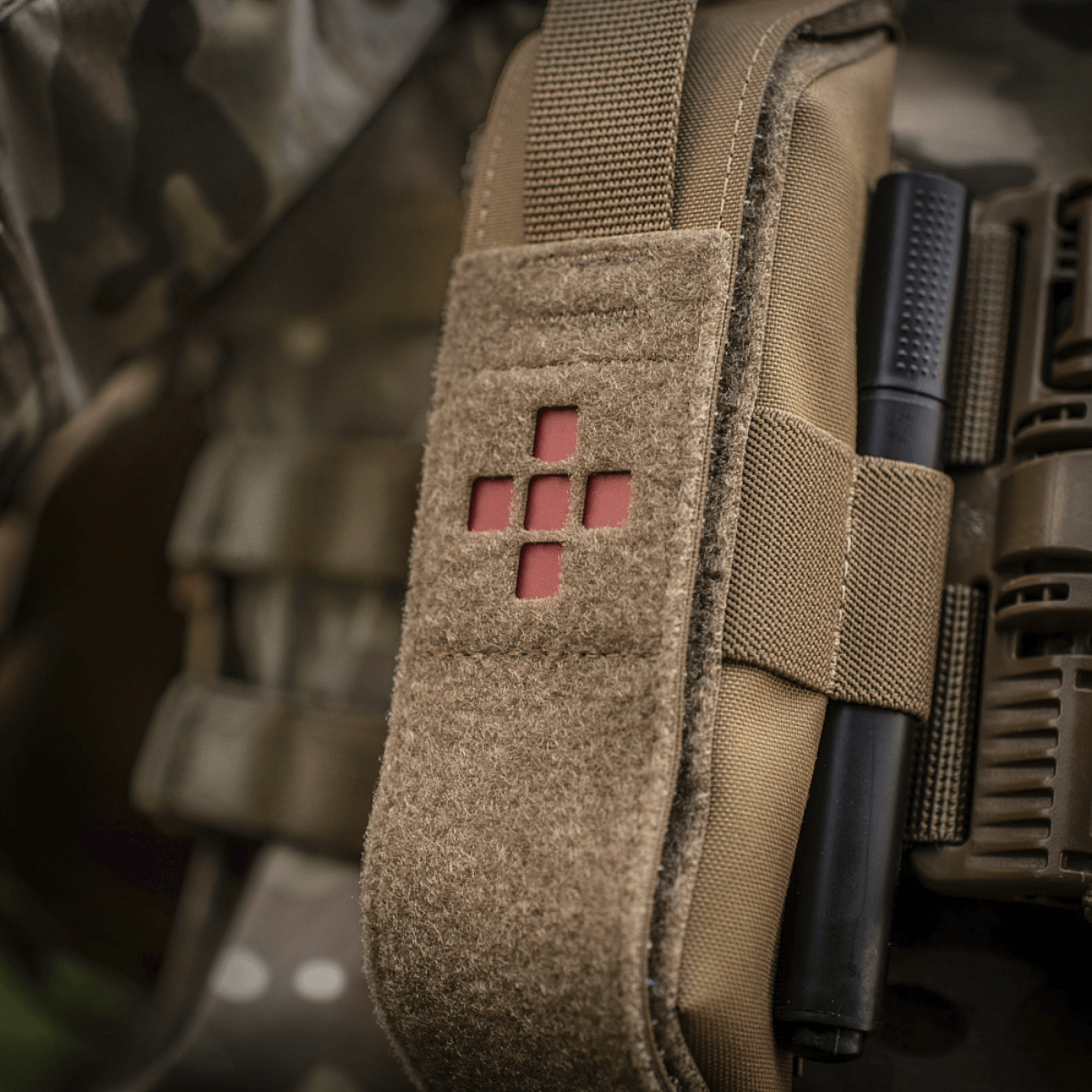 M-Tac Lomme til Tourniquet Closed i brug på en camouflagetaske, perfekt til pålidelig opbevaring af førstehjælpsudstyr.