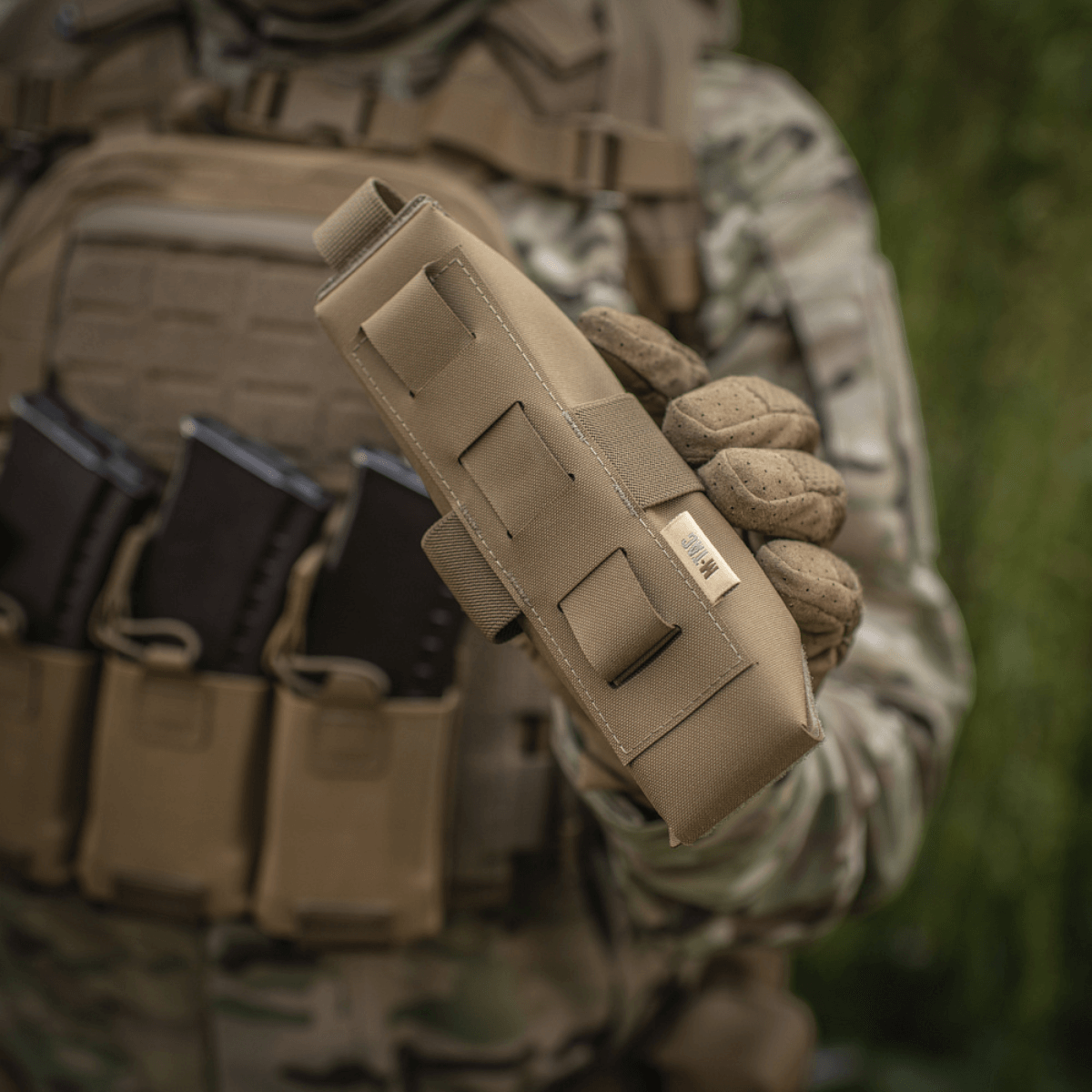 M-Tac Lomme til Tourniquet Closed i beige materiale i brug af militærpersonale, holdt foran skudsikker vest til førstehjælpsbeskyttelse.