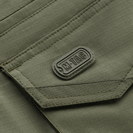 Nærbillede af M-Tac Shorts Aggressor Gen.II Flex lommedesign i rip-stop stof, grøn farve, med taktisk syning og M-Tac mærkning.