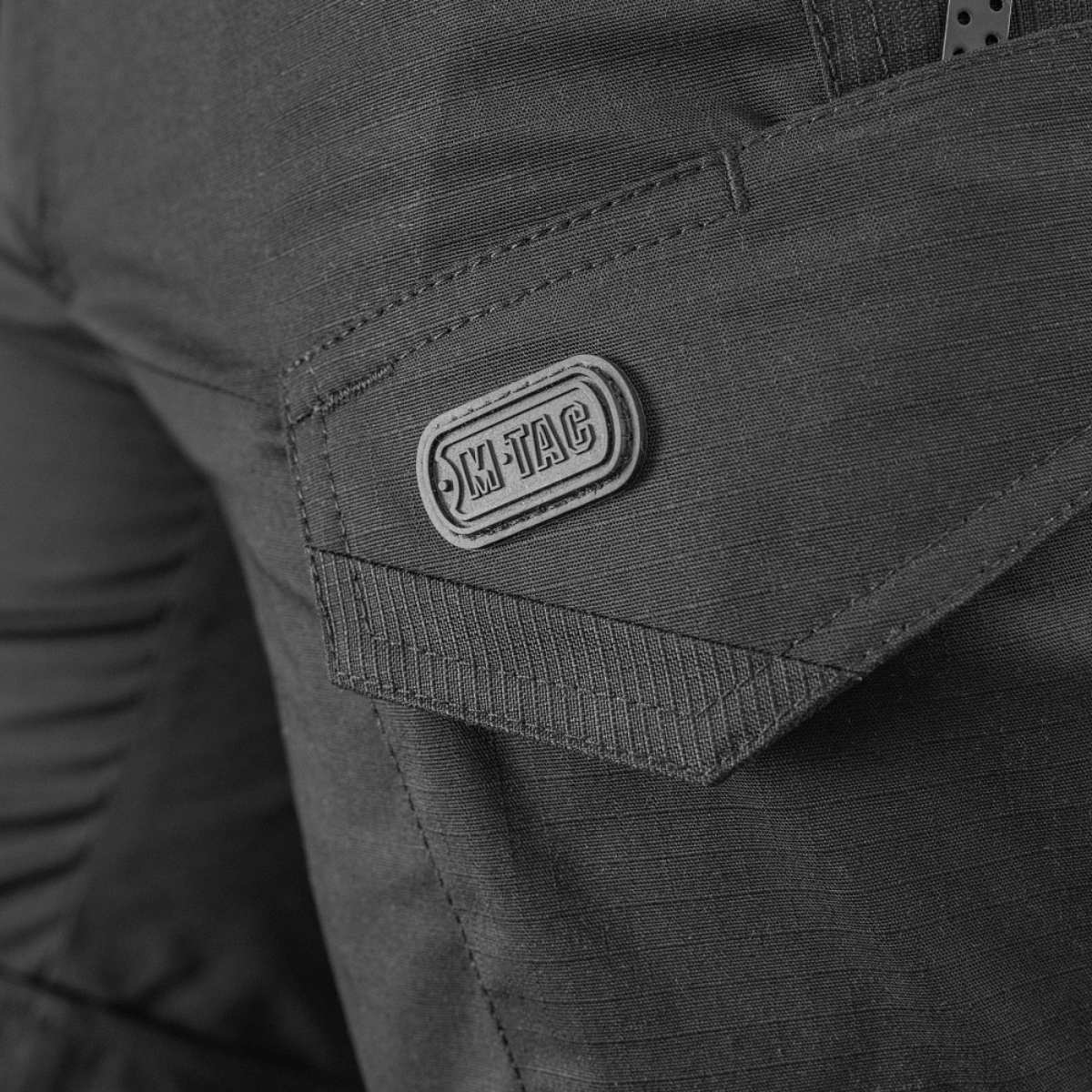 Detalje af M-Tac Shorts Aggressor Short med synlig lomme og M-Tac logo, fremstillet i slidstærkt rip-stop stof.