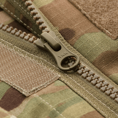Nærbillede af YKK-lynlås på M-Tac Jakke Military Elite NYCO i MultiCam mønster, viser detaljeret konstruktion og design.