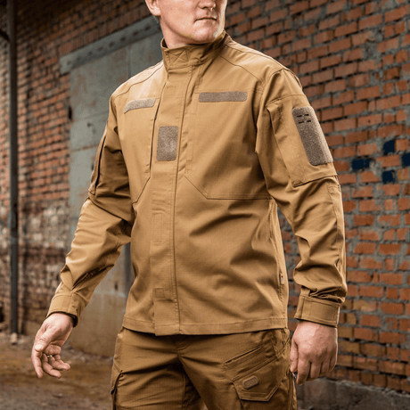 Mand iført M-Tac Jakke Patrol Flex i en urban baggrund viser taktiske detaljer som velcropaneler og skjulte lommer.